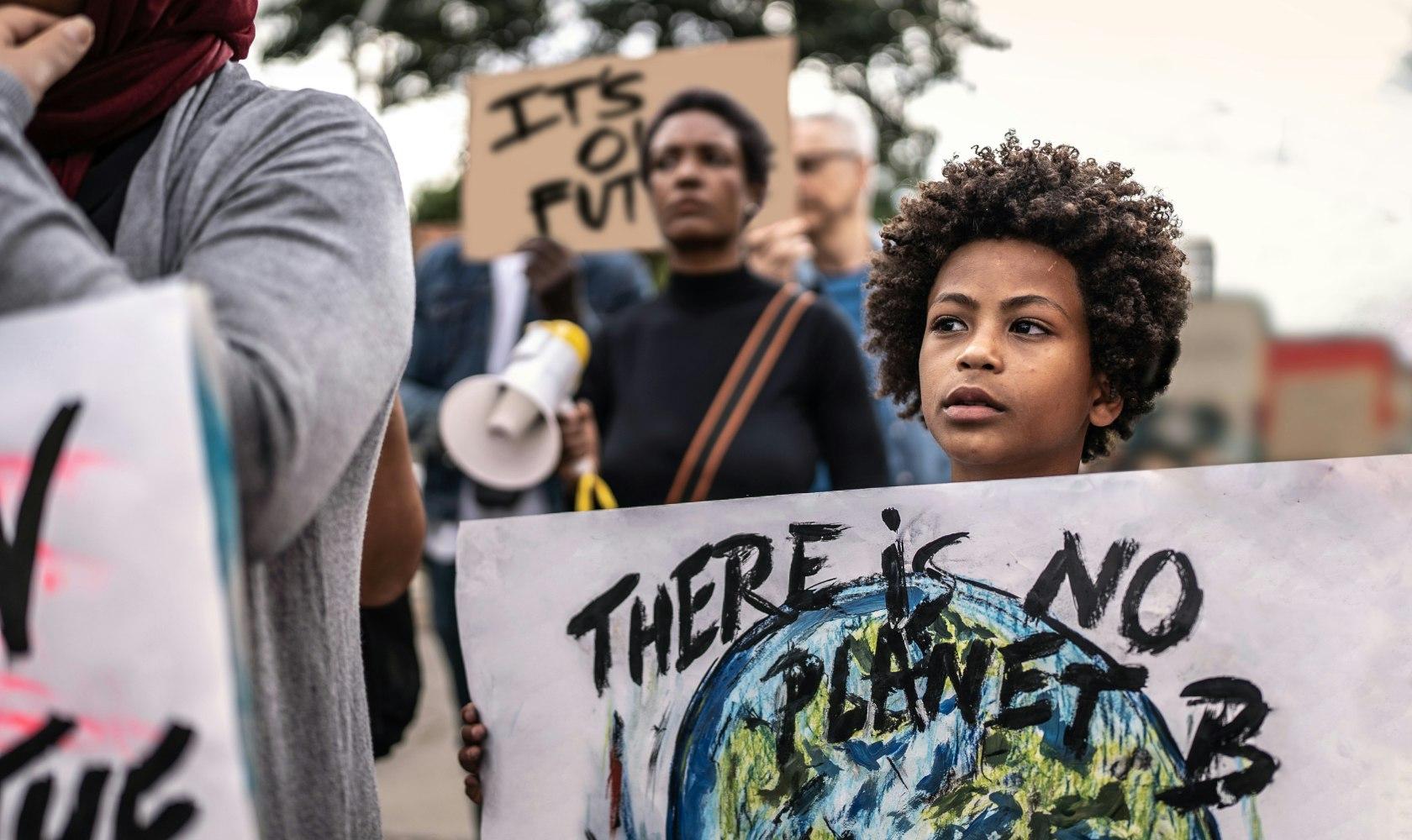 Child holding sign that says 'There is no Planet B'
