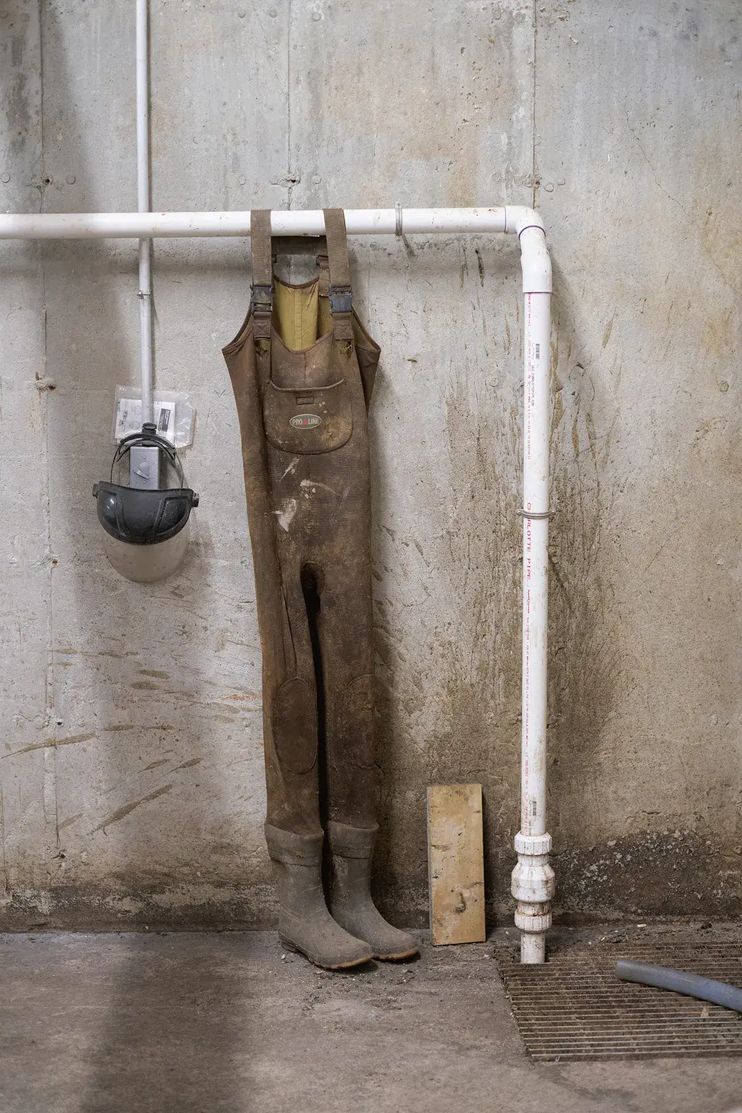 At Goodrich Farm, well-worn overalls hang on pipes that carry manure out of the cow barns.